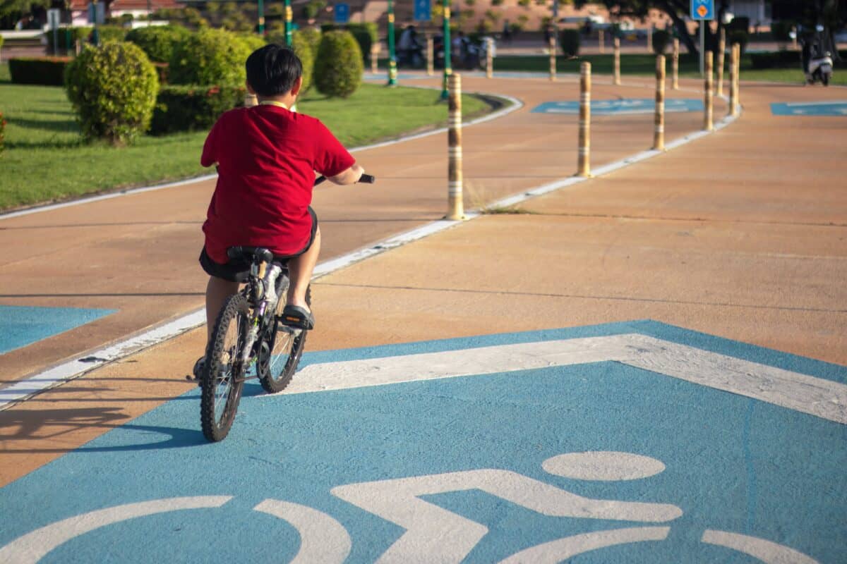 A boy riding a bicycle without protective gear on the bike lane